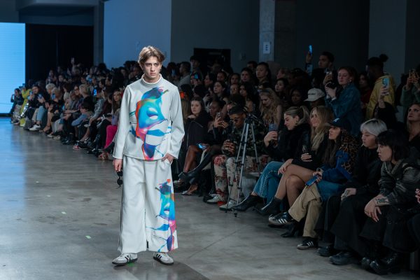 NYFWGlobalFashion A model walking down a runway with a white shirt with a colorful splash print and matching pants.
