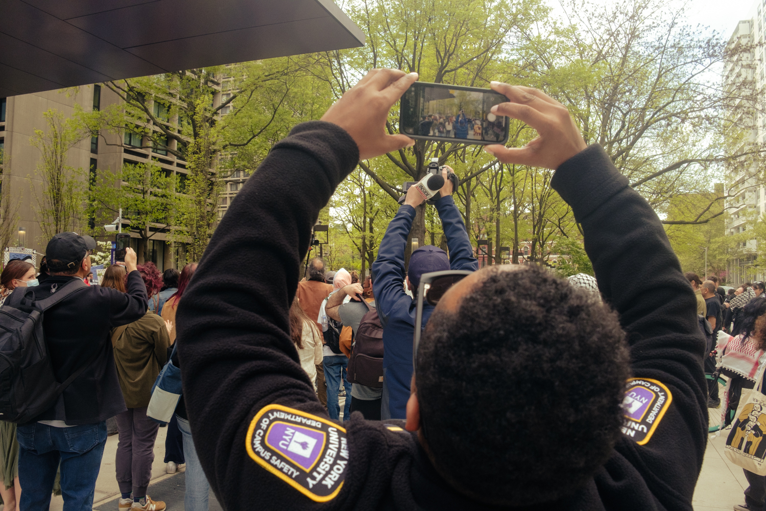 IDEA3800 A Campus Safety officer takes a photo of a cameraman filming the encampment.